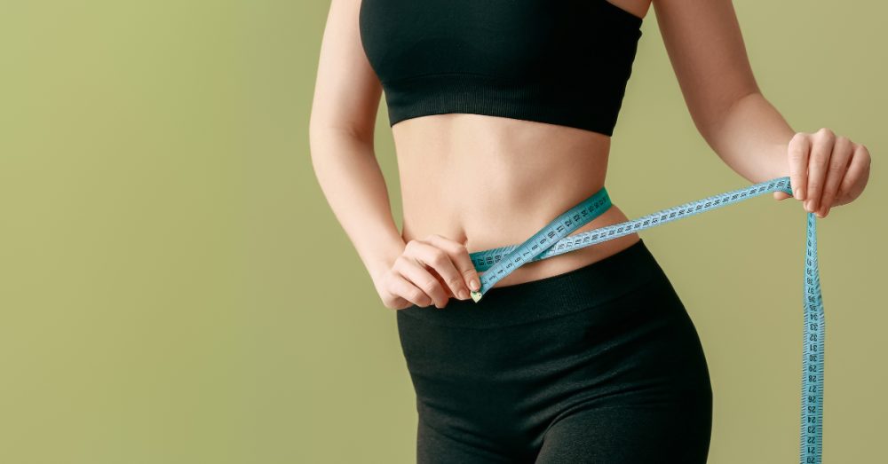 Woman measuring her waist, signifying weight loss